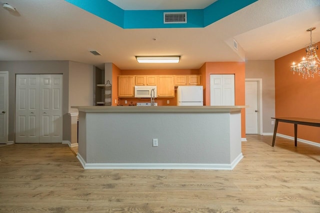 kitchen with white appliances, light hardwood / wood-style floors, a chandelier, and light brown cabinets