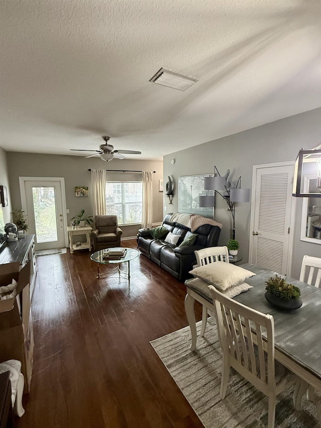 living room featuring ceiling fan, a textured ceiling, and dark hardwood / wood-style flooring