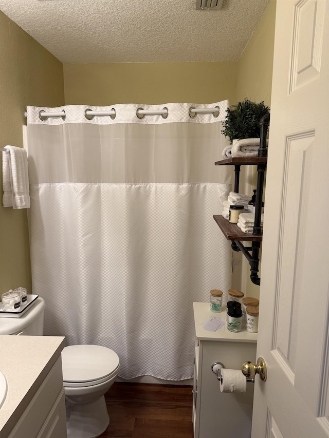 full bathroom featuring toilet, a textured ceiling, hardwood / wood-style floors, and vanity