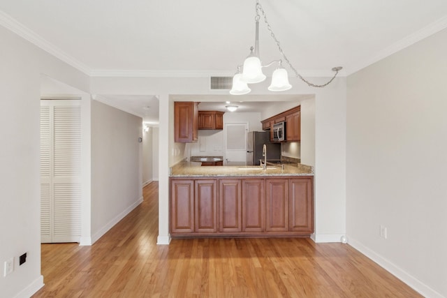 kitchen with decorative light fixtures, light wood-type flooring, ornamental molding, appliances with stainless steel finishes, and kitchen peninsula