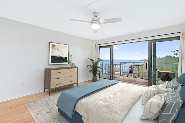 bedroom featuring hardwood / wood-style flooring, access to outside, ceiling fan, and a water view