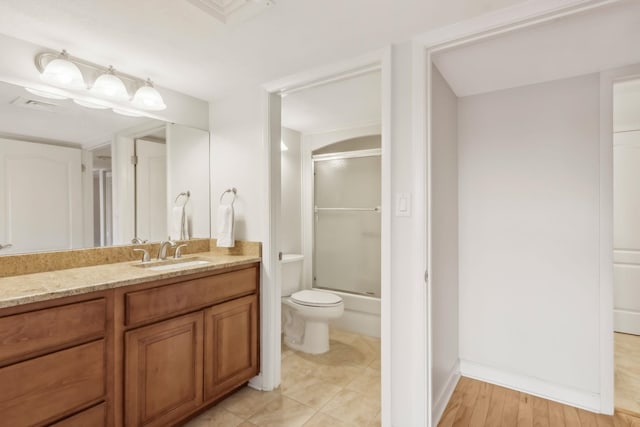 full bathroom featuring bath / shower combo with glass door, vanity, and toilet