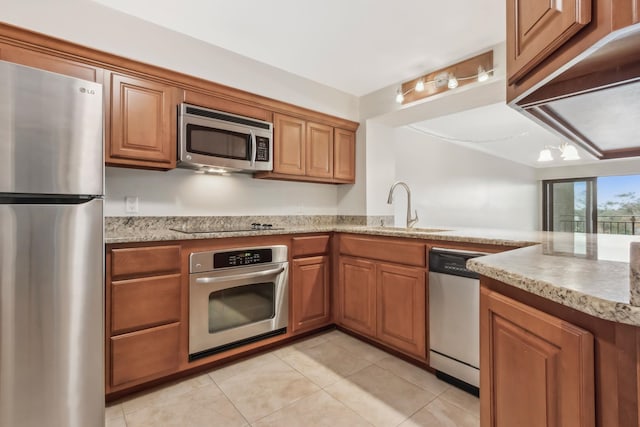 kitchen with sink, light stone counters, light tile patterned floors, kitchen peninsula, and stainless steel appliances