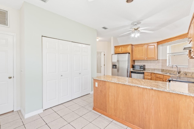 kitchen featuring stainless steel appliances, sink, kitchen peninsula, and light stone countertops