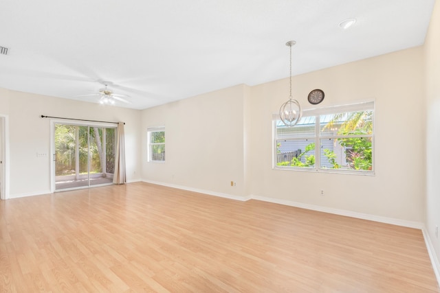 spare room with ceiling fan with notable chandelier and light hardwood / wood-style flooring