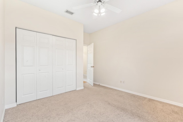 unfurnished bedroom featuring ceiling fan, a closet, and light colored carpet