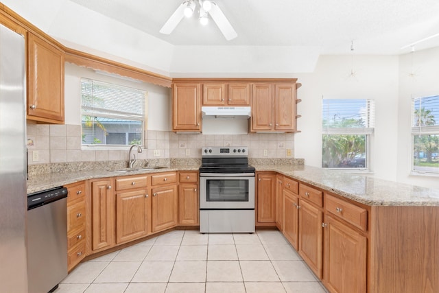 kitchen featuring light stone countertops, appliances with stainless steel finishes, kitchen peninsula, and sink