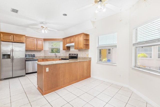 kitchen with backsplash, kitchen peninsula, appliances with stainless steel finishes, light tile patterned floors, and light stone counters