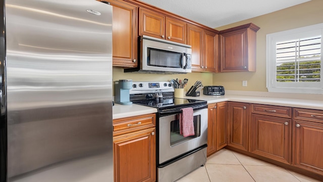 264 Gibraltar Ct Unit 101, Saint Augustine, FL 32080 - kitchen with appliances with stainless steel finishes, light countertops, light tile patterned flooring, and brown cabinets