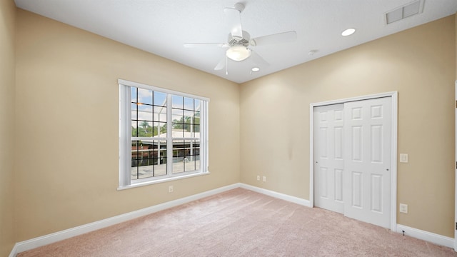 unfurnished bedroom featuring ceiling fan, a closet, and light colored carpet