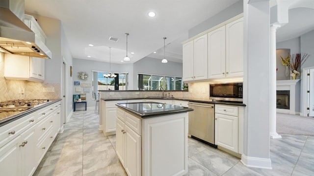 kitchen featuring appliances with stainless steel finishes, tasteful backsplash, wall chimney exhaust hood, pendant lighting, and a center island