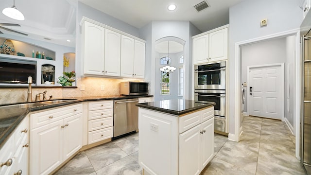 kitchen with a center island, hanging light fixtures, tasteful backsplash, white cabinetry, and stainless steel appliances