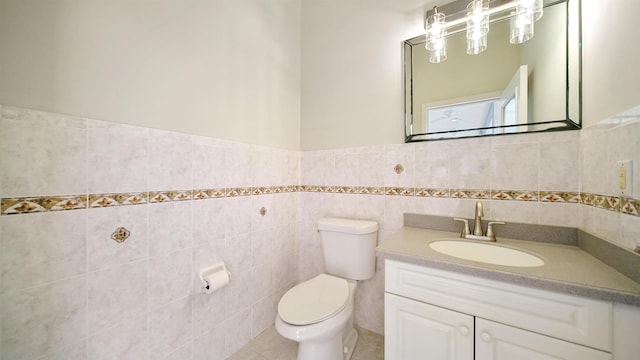 bathroom featuring tile patterned flooring, vanity, toilet, and tile walls