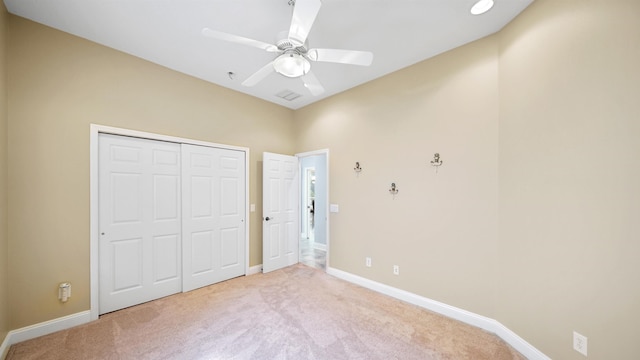 unfurnished bedroom with ceiling fan, light colored carpet, and a closet