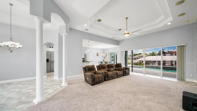 carpeted living room with ceiling fan with notable chandelier, a tray ceiling, and ornate columns