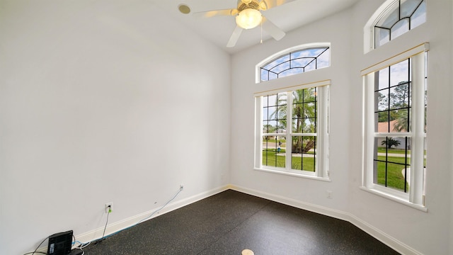 empty room with ceiling fan and high vaulted ceiling