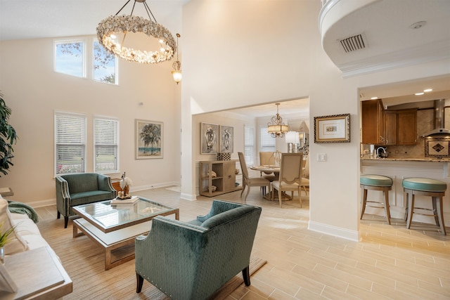 living room with a notable chandelier, a wealth of natural light, a high ceiling, and light wood-type flooring