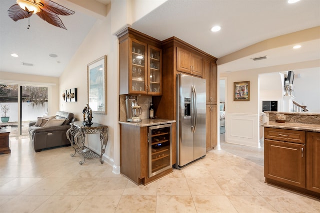 kitchen featuring lofted ceiling, stainless steel fridge, beverage cooler, light tile patterned floors, and light stone countertops