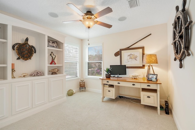 home office with light carpet, ceiling fan, and a textured ceiling