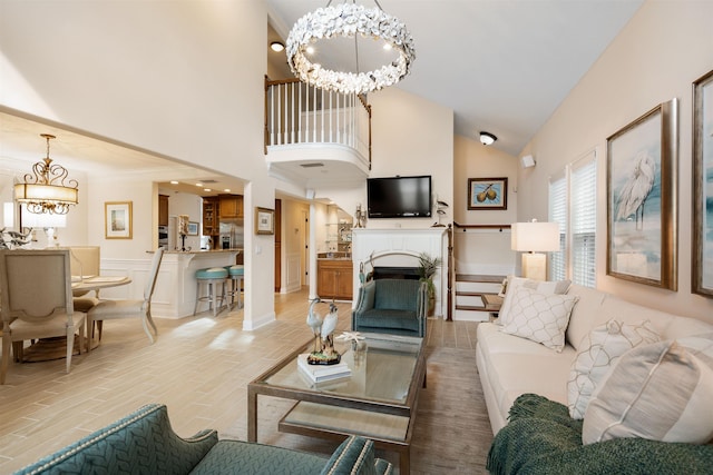 living room featuring high vaulted ceiling, an inviting chandelier, and light hardwood / wood-style floors