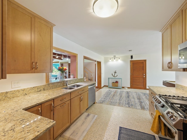 kitchen with kitchen peninsula, light stone countertops, sink, and stainless steel appliances