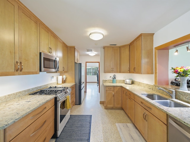 kitchen with light stone countertops, sink, light brown cabinets, and appliances with stainless steel finishes