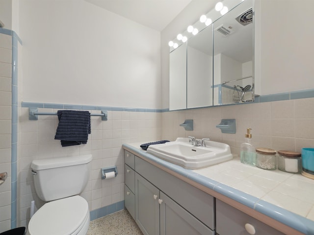 bathroom featuring vanity, toilet, and tile walls