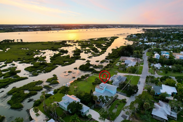 aerial view at dusk featuring a water view