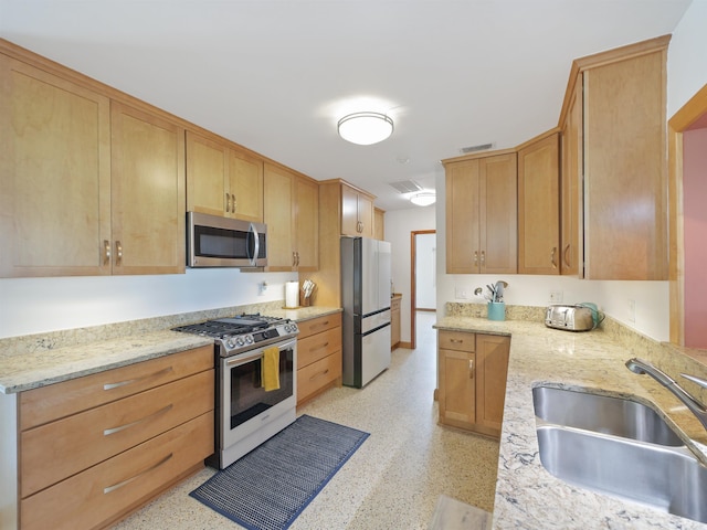 kitchen featuring light stone counters, sink, and appliances with stainless steel finishes