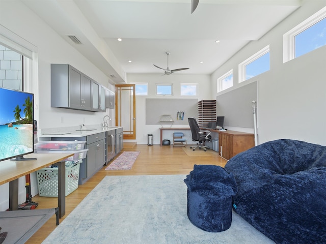 living room featuring ceiling fan, light hardwood / wood-style floors, and sink