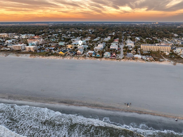 aerial view at dusk featuring a beach view and a water view