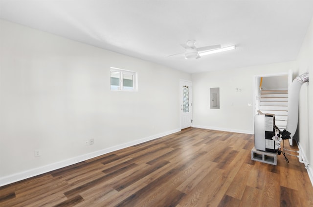 living room featuring heating unit, dark hardwood / wood-style flooring, electric panel, and ceiling fan