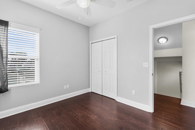 unfurnished bedroom featuring dark wood-type flooring, a textured ceiling, ceiling fan, and a closet