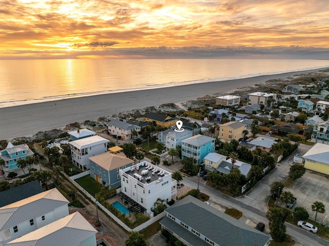 aerial view at dusk with a water view and a view of the beach