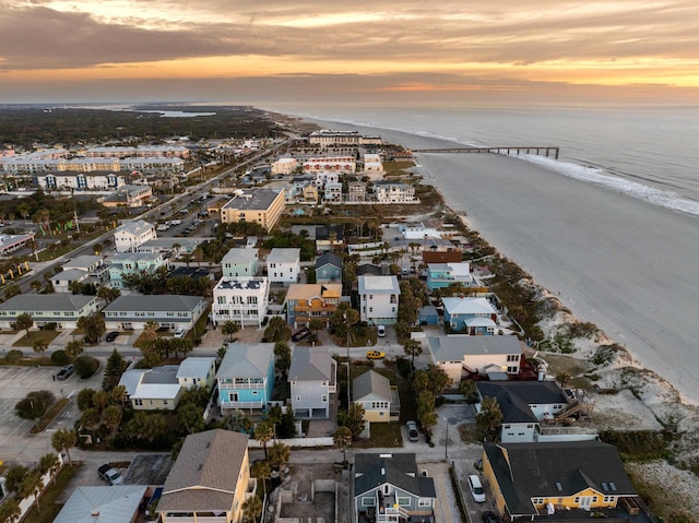 aerial view at dusk with a water view and a view of the beach