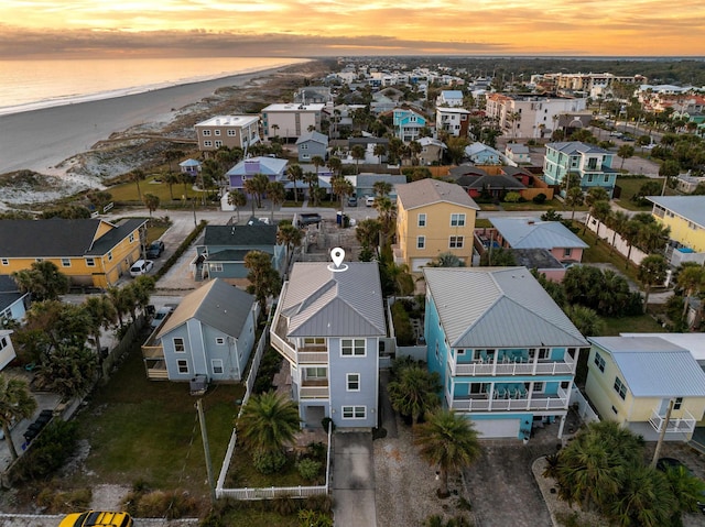 aerial view at dusk with a water view and a view of the beach