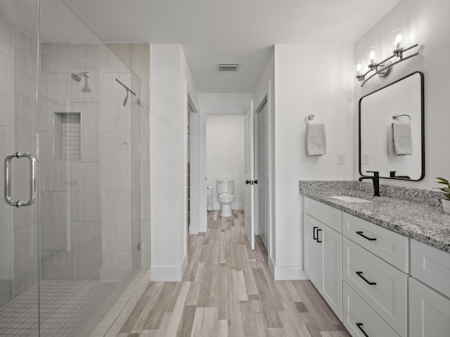 bathroom with toilet, walk in shower, wood-type flooring, and vanity