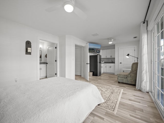 bedroom with ensuite bath, stainless steel refrigerator, ceiling fan, and light hardwood / wood-style flooring