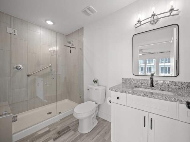 bathroom featuring vanity, hardwood / wood-style floors, a shower with shower door, and toilet