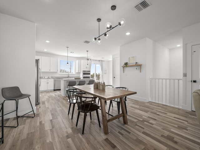 dining space featuring light hardwood / wood-style flooring and an inviting chandelier