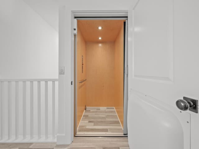 details featuring elevator and hardwood / wood-style flooring