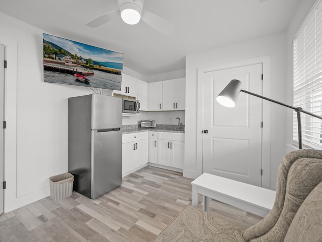 kitchen with sink, white cabinets, light wood-type flooring, ceiling fan, and appliances with stainless steel finishes