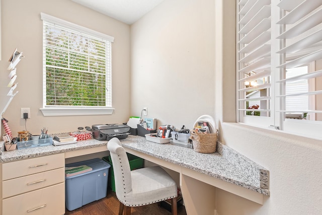 office featuring dark hardwood / wood-style flooring, built in desk, and a healthy amount of sunlight