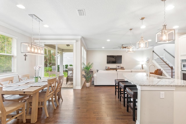 dining space featuring ceiling fan, dark hardwood / wood-style floors, a textured ceiling, crown molding, and sink