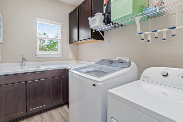 laundry area featuring cabinets, light hardwood / wood-style floors, separate washer and dryer, and sink