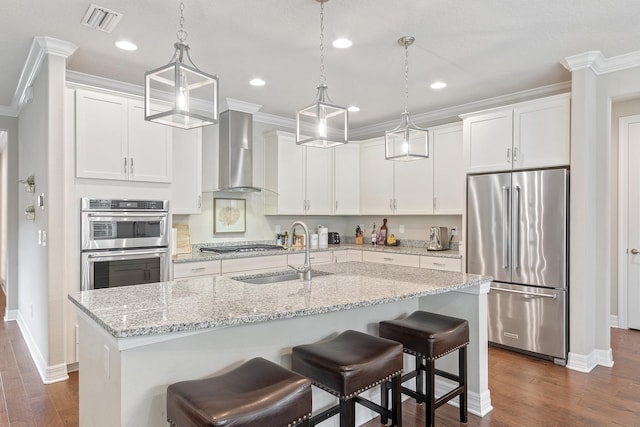 kitchen featuring white cabinets, sink, wall chimney range hood, and stainless steel appliances