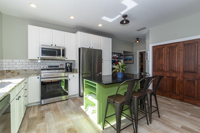 kitchen featuring white cabinetry, backsplash, light hardwood / wood-style floors, and appliances with stainless steel finishes