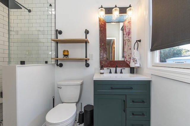 bathroom featuring a tile shower, vanity, and toilet