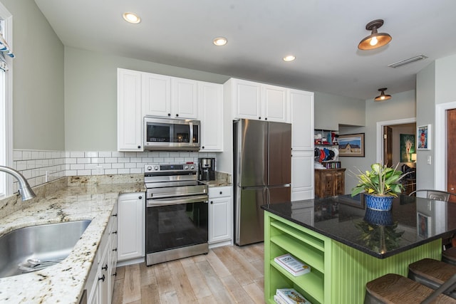 kitchen featuring sink, white cabinetry, stainless steel appliances, light stone counters, and decorative backsplash