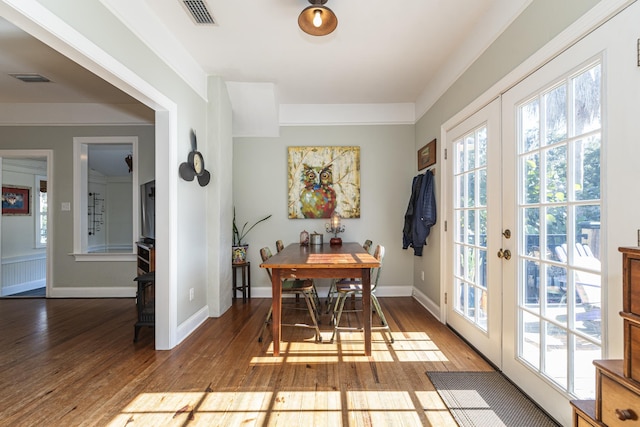 dining room with hardwood / wood-style floors, ornamental molding, and french doors